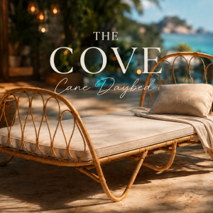Elegant handcrafted cane daybed with curved woven rattan frame and slim upholstered mattress, styled in a luxury tropical patio setting with warm ambient lighting and coastal resort-inspired décor.