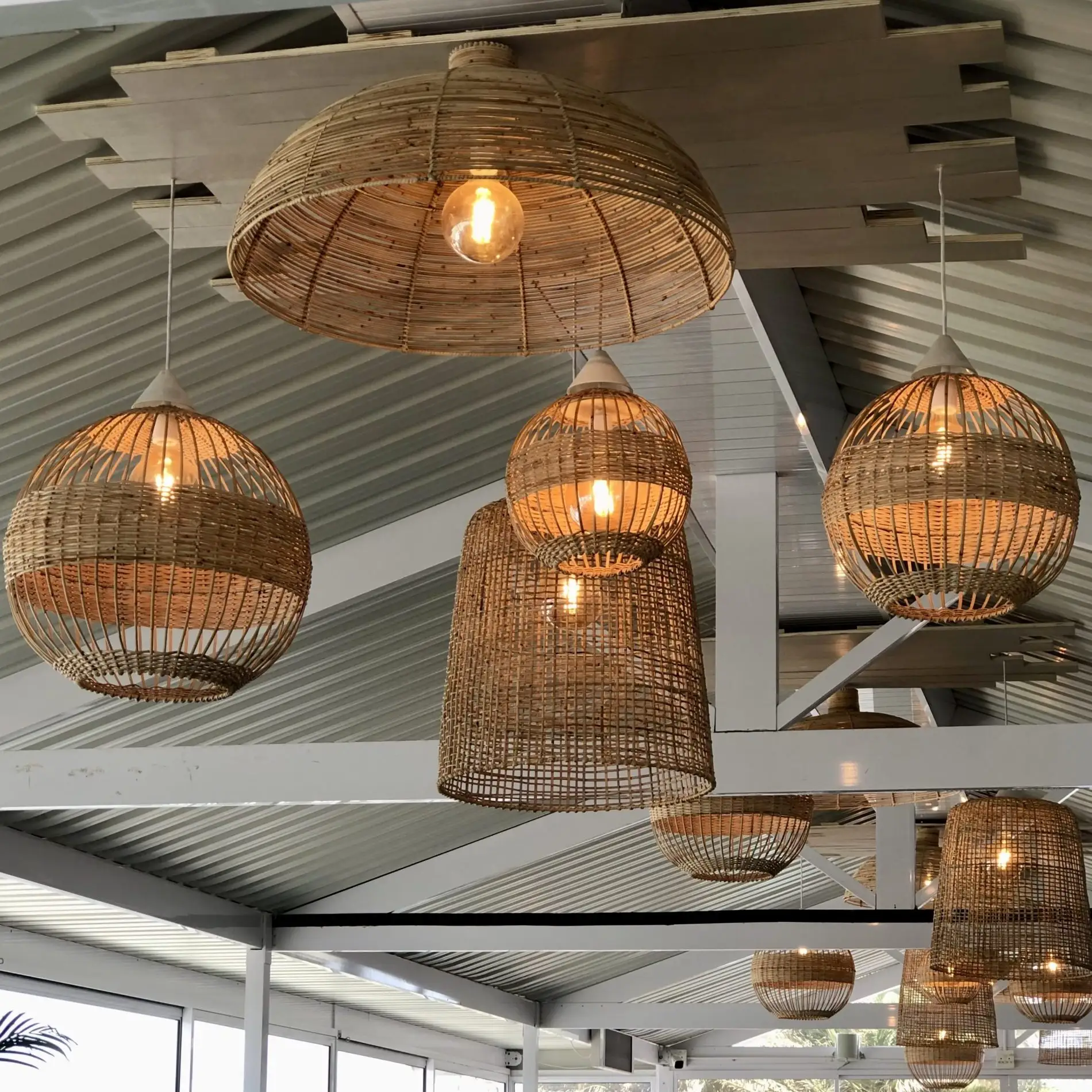 Cluster of handcrafted woven wicker pendant lampshades suspended in a modern interior creating warm ambient lighting.