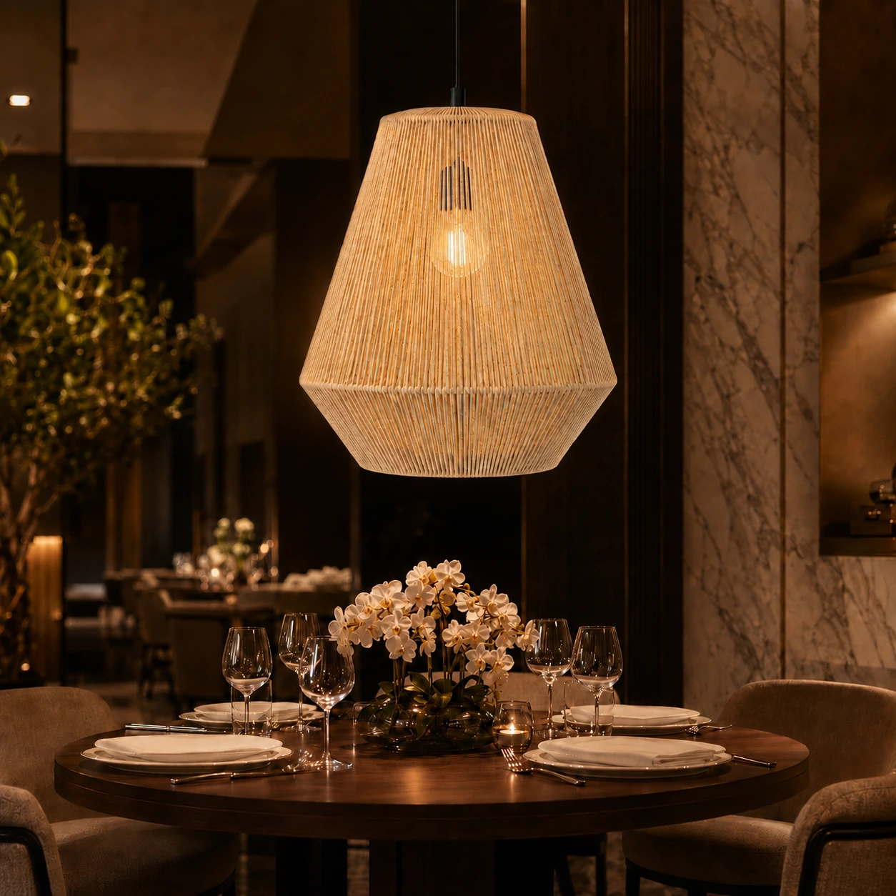 Drift Halo natural Danish cord pendant lamp glowing above an elegant five-star hotel dining table