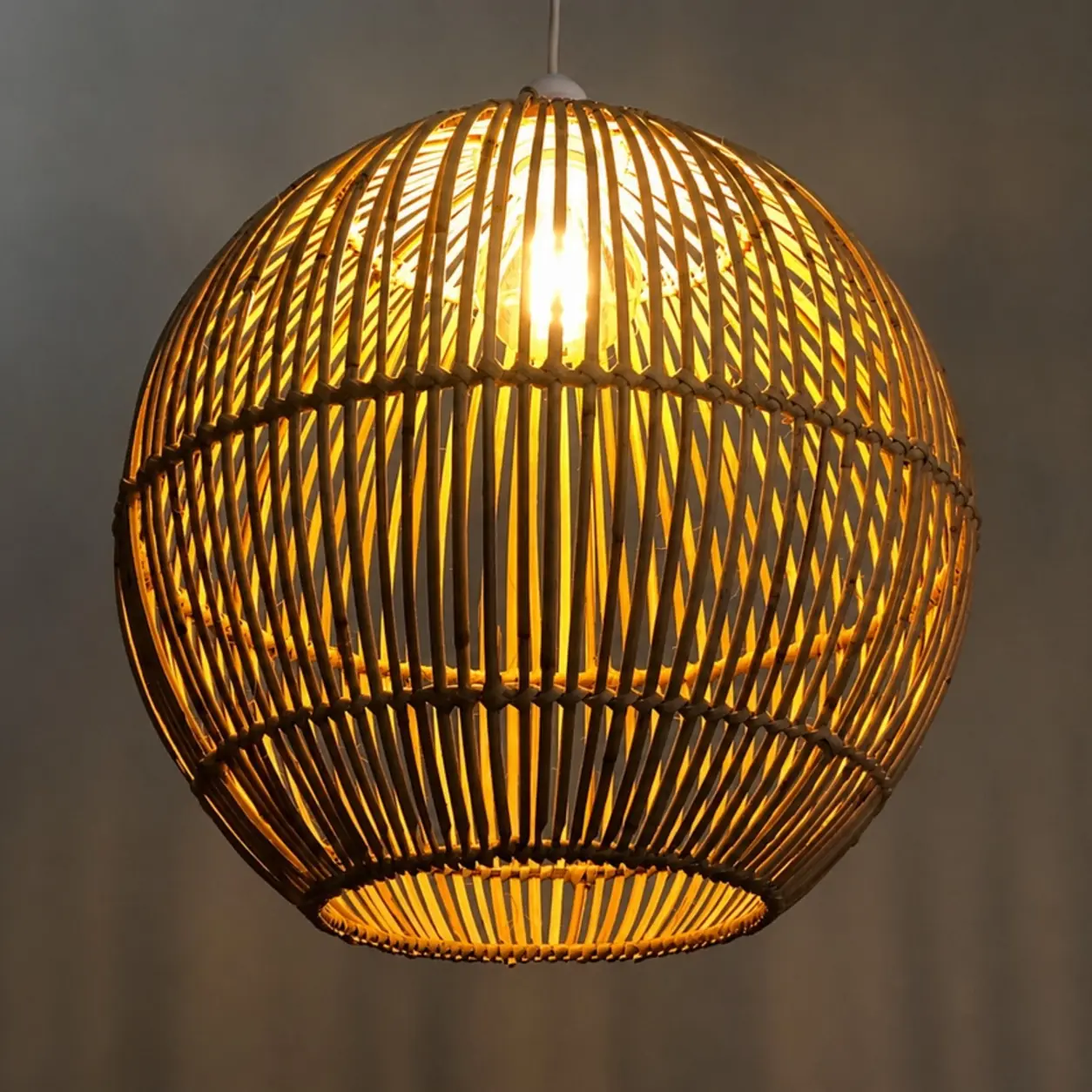 Illuminated Tropicana spherical cane pendant lampshade casting a warm patterned glow